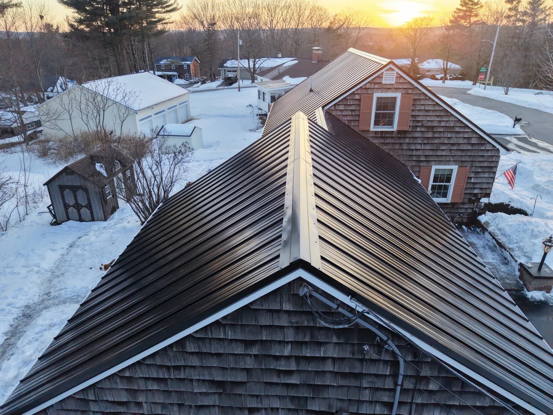 Completed standing seam metal roof photographed from above at sunset on a Southern Maine GraniteShield project