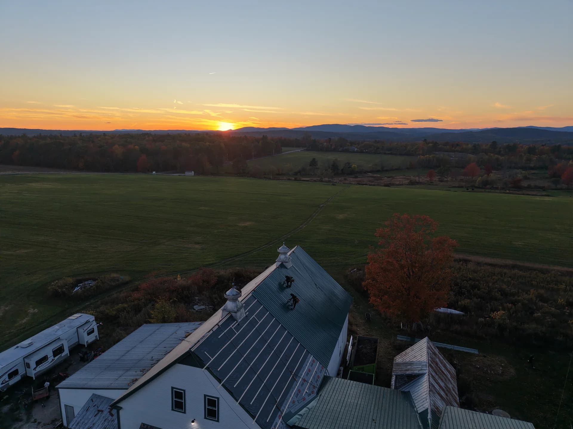 Metal roof installation on historic Maine barn - standing seam roofing with traditional cupolas