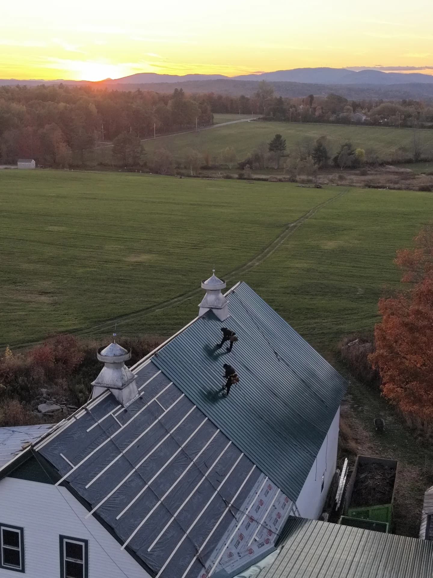 GraniteShield standing seam metal roof barn with cupolas at sunset Maine