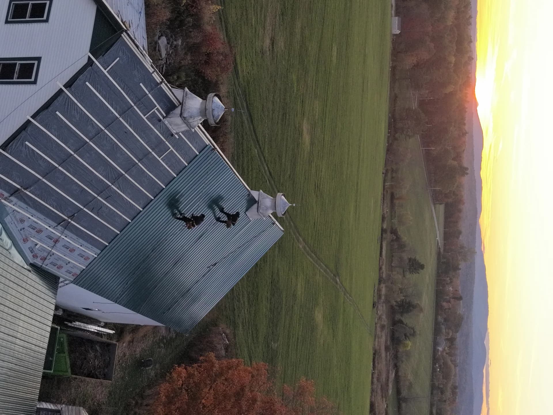 GraniteShield standing seam metal roof barn with cupolas at sunset Maine