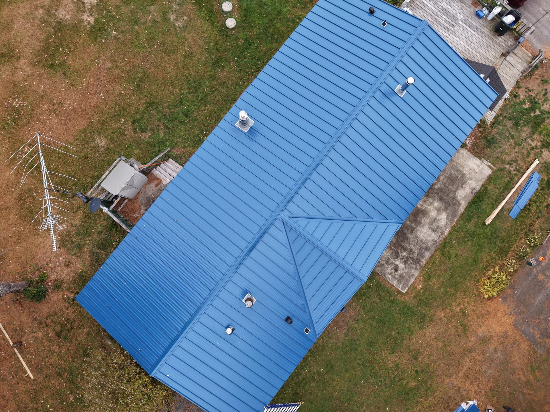 Professional standing seam metal roof installation - close-up aerial view of blue metal panels